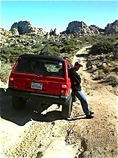 Joe leans against Keith's Jeep, as the gnarly road has caused our pass...